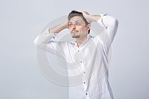 Young attractive surprised brunette man in white shirt on gray