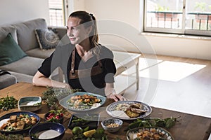 Young attractive swedish food blogger posing in front of a table full of food dishes. Young girl sitting in front of a wooden