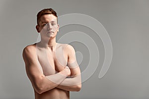 Young attractive swimmer in excellent physical shape in purple swimming shorts, on a gray background, copy space