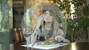 Young attractive tattooed blond girl in fancy dinner restaurant licking greasy fingers inappropriate behaviour in public