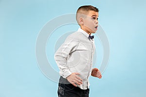 The young attractive teen boy looking suprised isolated on blue