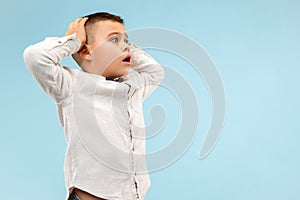 The young attractive teen boy looking suprised isolated on blue