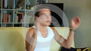 Young attractive teenager boy jumping on sofa watc