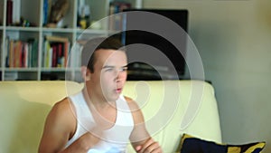 Young attractive teenager boy jumping on sofa watc