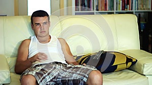 Young attractive teenager boy watching television on sofa