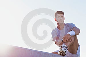 Young attractive thoughtful man sitting and wearing sports wear