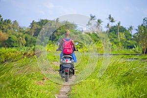 Young attractive tourist afro American black woman riding motorbike happy in beautiful Asia countryside along green rice fields s