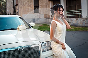 Young attractive VIP Woman in the dress stand near white limousine