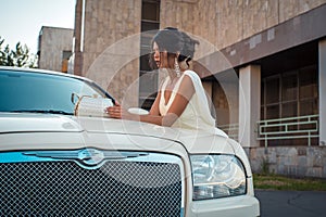 Young attractive VIP Woman in the dress stand near white limousine