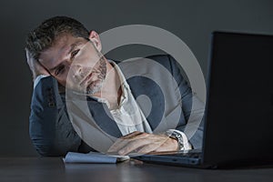 Young attractive wasted and tired entrepreneur man working late night at office laptop computer desk exhausted and sleepy in