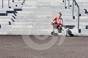 Young attractive woman adjusting safety gear while wearing rollerblades