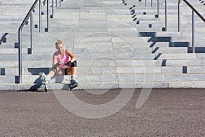 Young attractive woman adjusting safety gear while wearing rollerblades