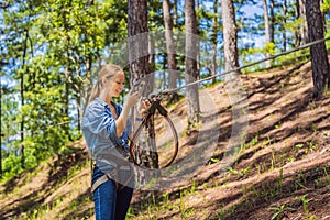 Young attractive woman in adventure rope park in safety equipment