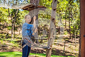 Young attractive woman in adventure rope park in safety equipment