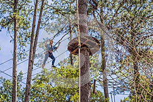 Young attractive woman in adventure rope park in safety equipment