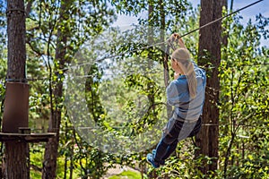 Young attractive woman in adventure rope park in safety equipment