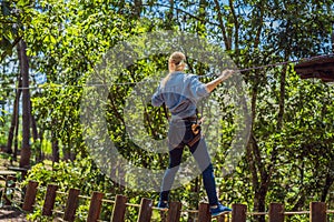 Young attractive woman in adventure rope park in safety equipment