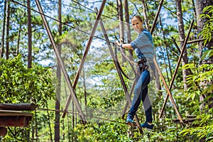 Young attractive woman in adventure rope park in safety equipment