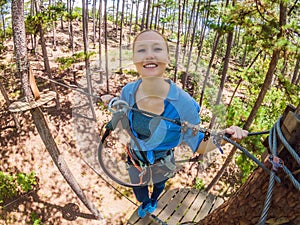 Young attractive woman in adventure rope park in safety equipment