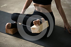 Young attractive woman in Agni stambhasana pose with block, clos