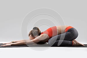 Young attractive woman in Balasana pose, grey studio background photo
