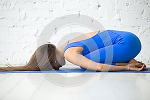 Young attractive woman in Balasana pose, white studio background photo