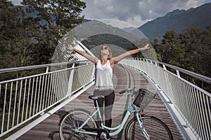 Young attractive woman with bicycle on a bridge