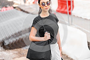 Young attractive woman in black blank t-shirt outdoors. Empty space. Copy space.