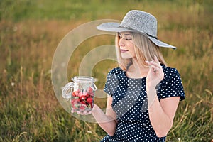 Young attractive woman in a blue dress at an outdoor picnic. A basket with daisies, watermelon, strawberries and a glass