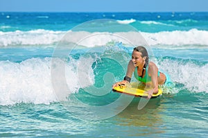 Young attractive woman bodyboards on surfboard with nice smile