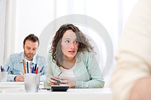 Young attractive woman cheating with mobile during exam