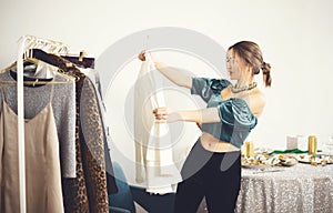 Young attractive woman choosing clothes for party or festive dinner at home, deciding what to wear