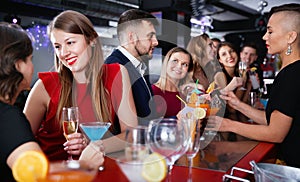 Young attractive woman with cocktails having fun with friends at nightclub