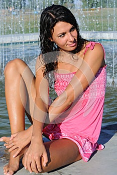 Young attractive woman cooling near the fountain