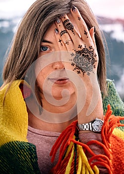 Young attractive woman covering eye with mehndi hand