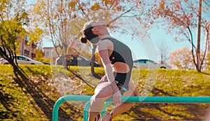 Young attractive woman doing exercises on parallel bars