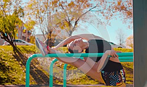 Young attractive woman doing exercises on parallel bars