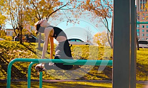 Young attractive woman doing exercises on parallel bars