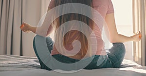 Young attractive woman doing morning practice at bed in home. Detail shot hands woman sitting in lotus pose yoga