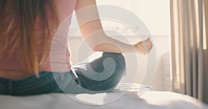 Young attractive woman doing morning practice at bed in home. Detail shot hands woman sitting in lotus pose yoga