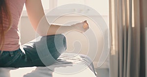 Young attractive woman doing morning practice at bed in home. Detail shot hands woman sitting in lotus pose yoga