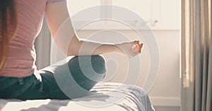 Young attractive woman doing morning practice at bed in home. Detail shot hands woman sitting in lotus pose yoga