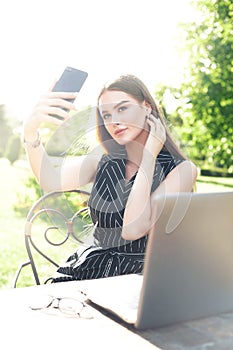 Young attractive woman doing selfie on phone in outdoor cafe