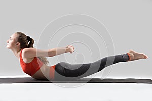 Young attractive woman in Double Leg Kicks exercise, grey studio