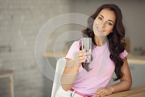 Young attractive woman drinking water on kitchen.
