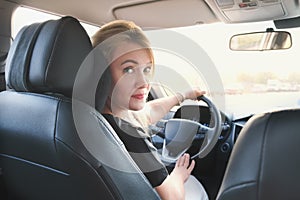 Young attractive woman drives a car. Beautiful blonde woman with long hair in a car while driving