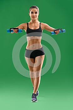 Young attractive woman with dumbbells in her hands posing in stu photo