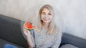 Young attractive woman eating watermelon. Woman looking at camera and smiling