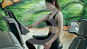 Young attractive woman enhancing her endurance while working out on an exercycle. portrait of a beautiful girl in the