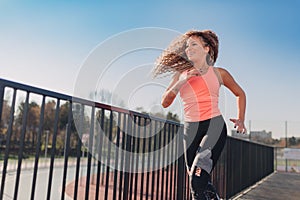 Young attractive woman enjoying outdoor physical exercise in the city running